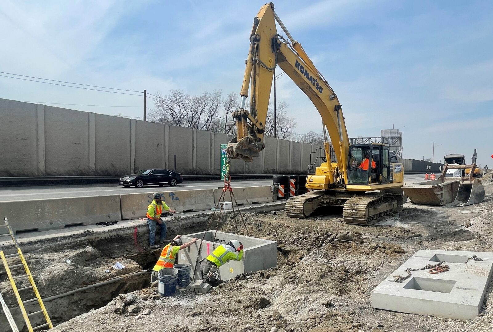 An image of a drainage structure being installed into the ground with construction equipment and workers.