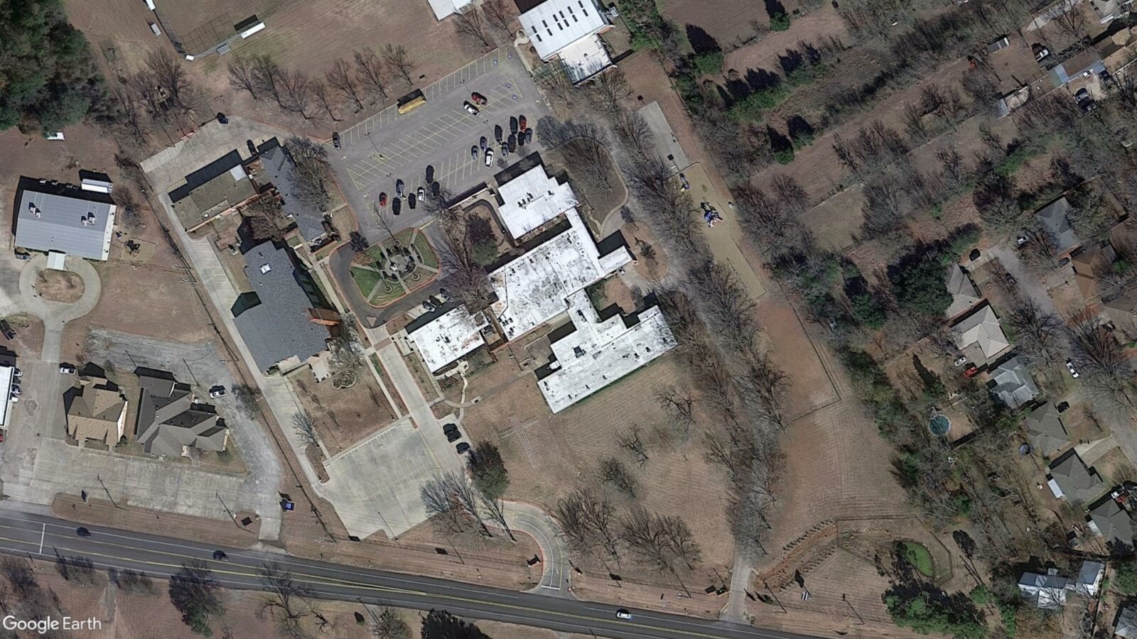 Aerial image of a complex with buildings, a courtyard, and a parking lot.