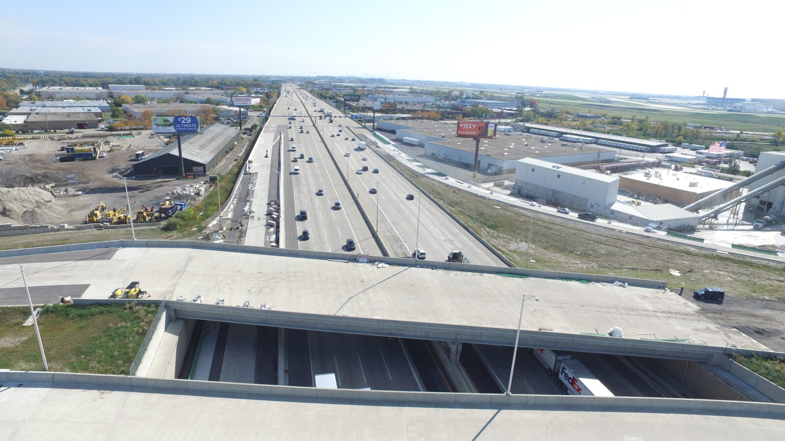 An image of an overpass over a highway under construction. The bridge deck is in place, but not yet painted with pavement markings.