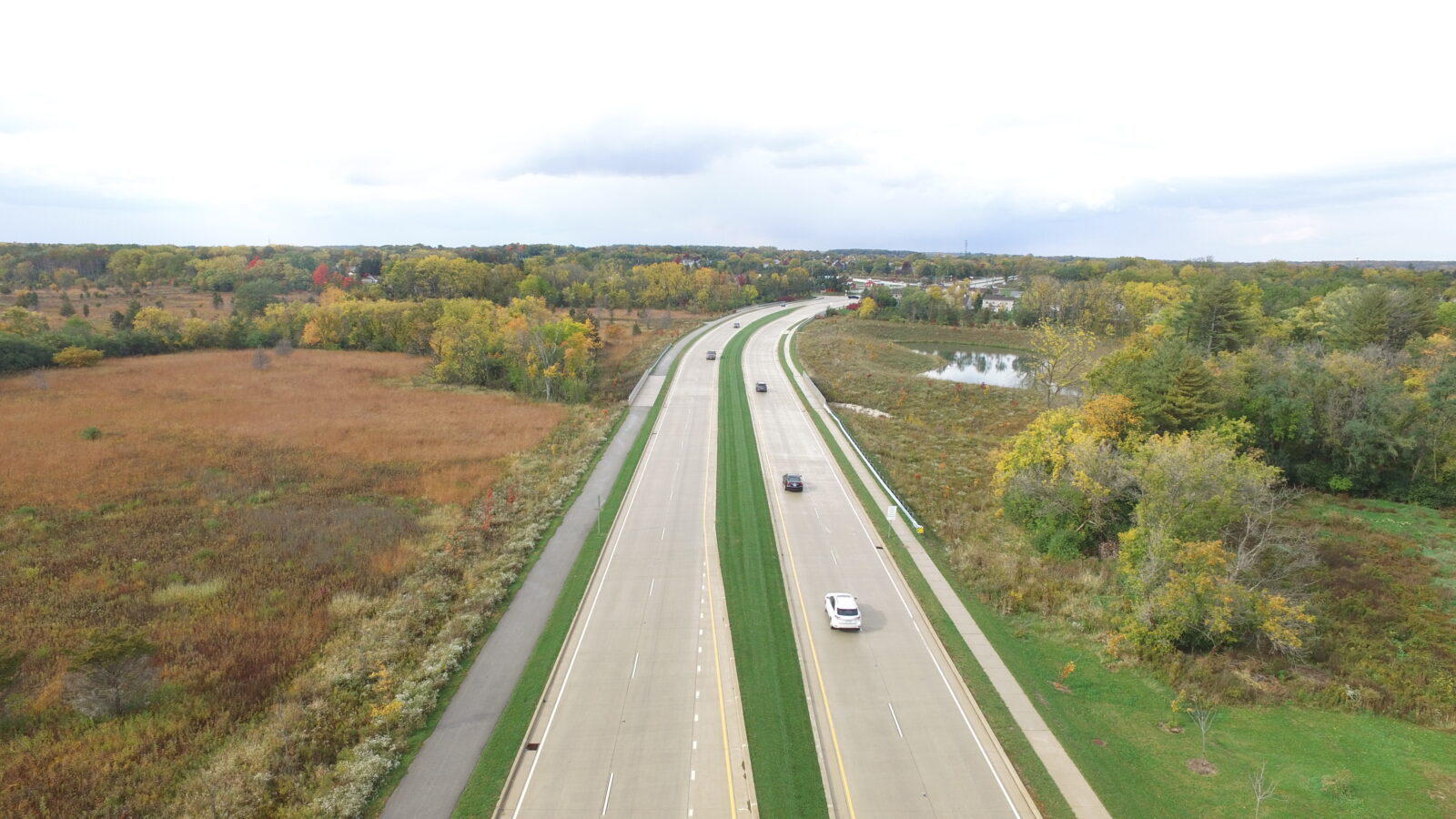 An aerial image of a divided highway, with two lanes in each direction and a sidewalk on either side.