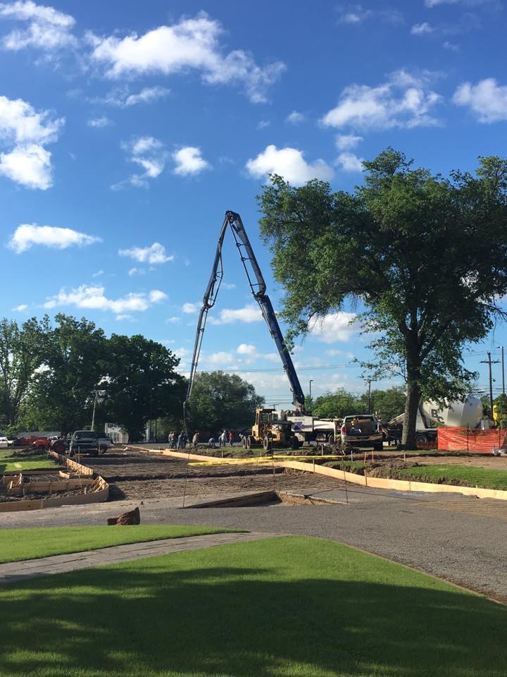 Image of a road being constructed next to grass and trees. A crane is visible.