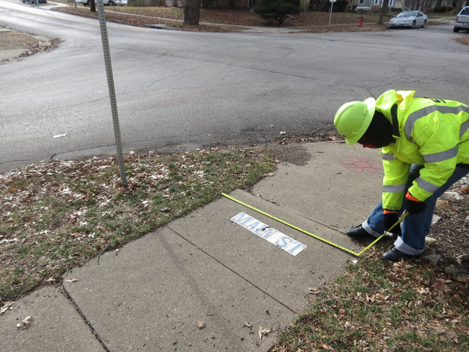 Image of a person in hi-vis clothing measuring sidewalk