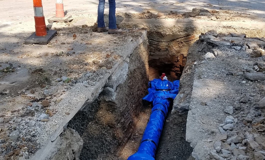 Image of an excavated ditch with a large pipe at the bottom of it.