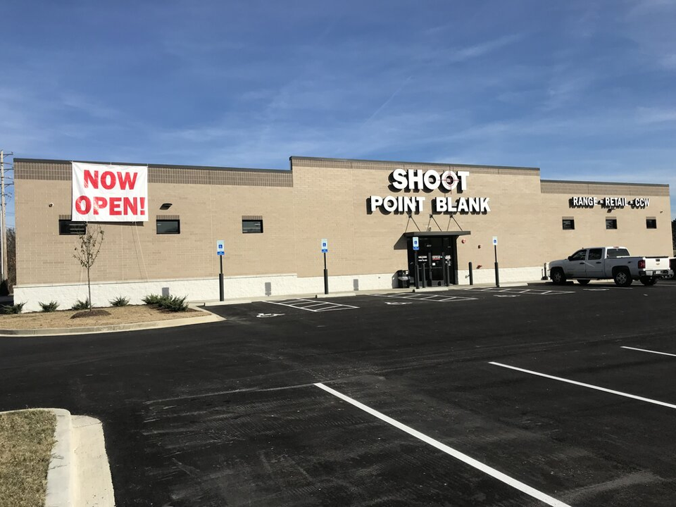 Image of a Point Blank store, taken from the parking lot. The building has a "Now Open!" banner on it.