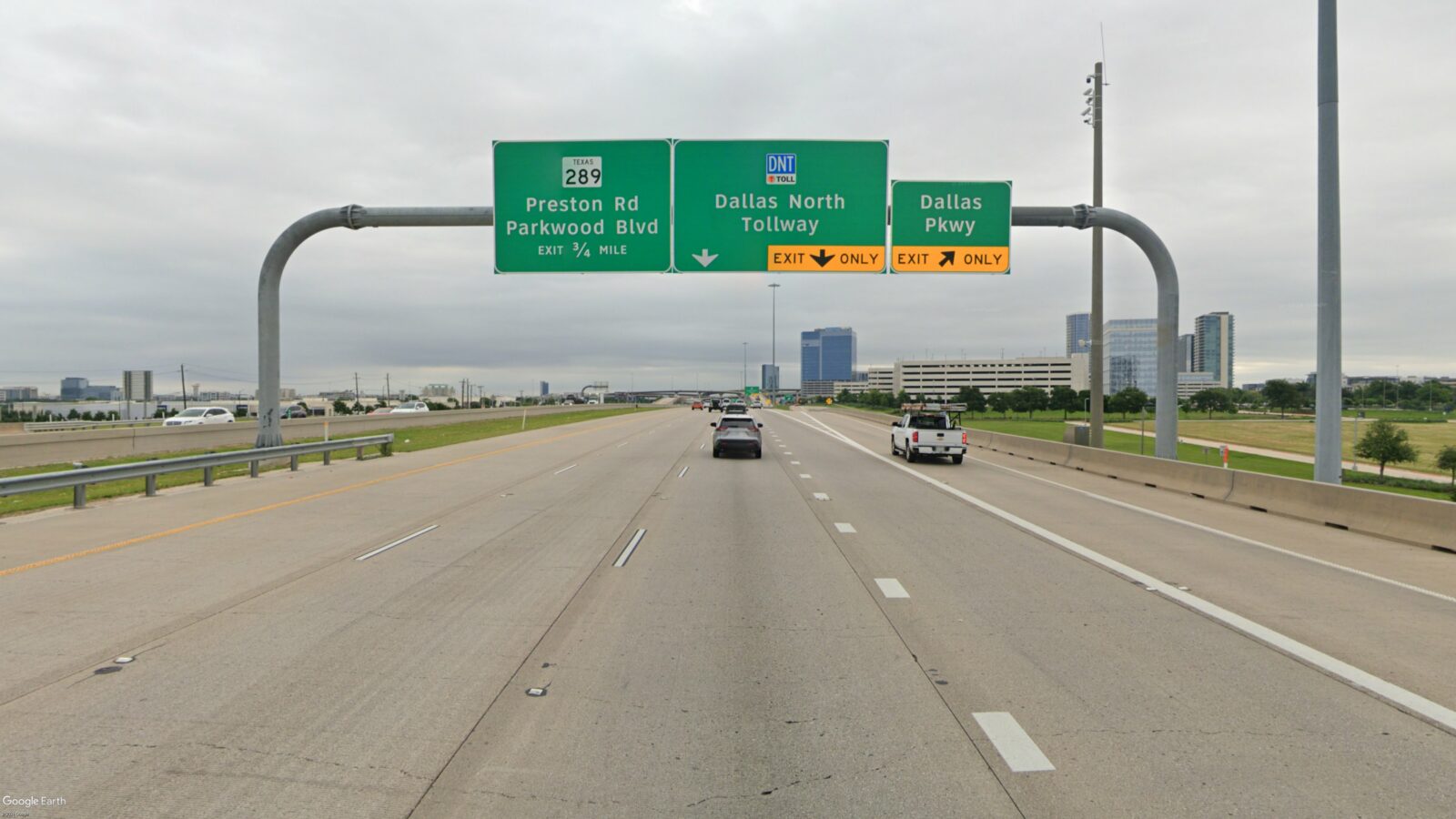 Image of an overhead sign bridge with signs, taken from the road