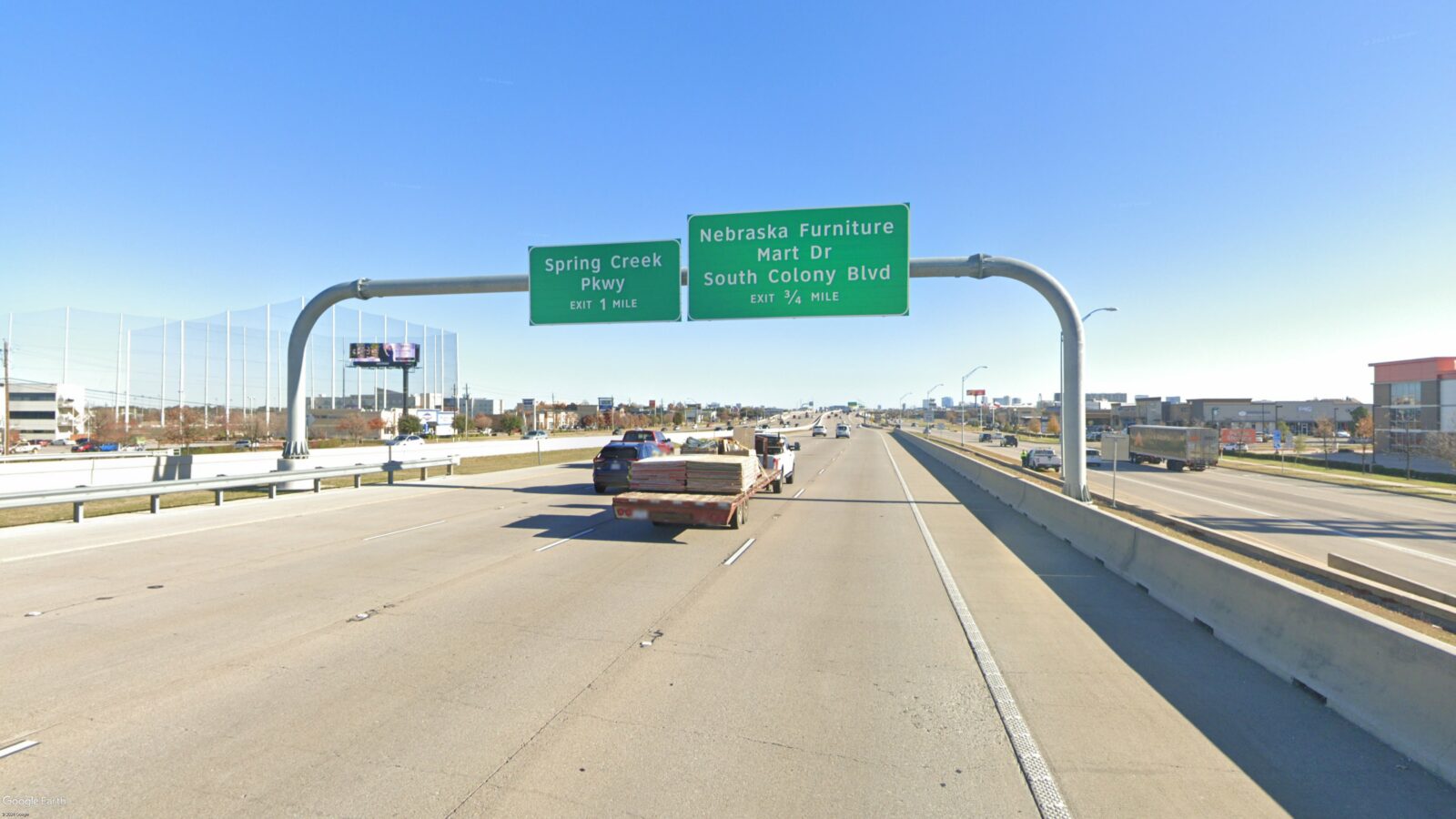 Image of an overhead sign bridge and signs, taken from the road.