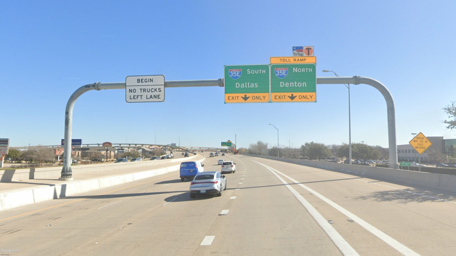 Image of an overhead sign bridge and signs, taken from the road.