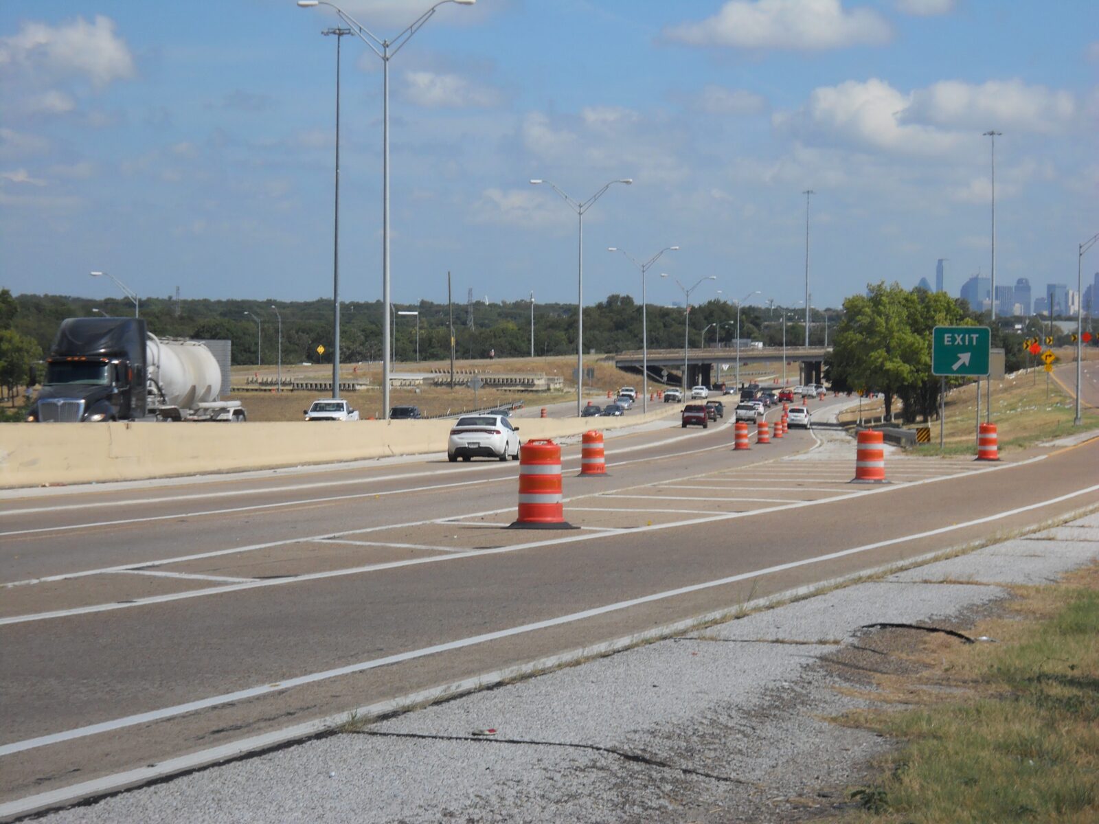 An image of a highway and exit ramp with orange traffic control barrels