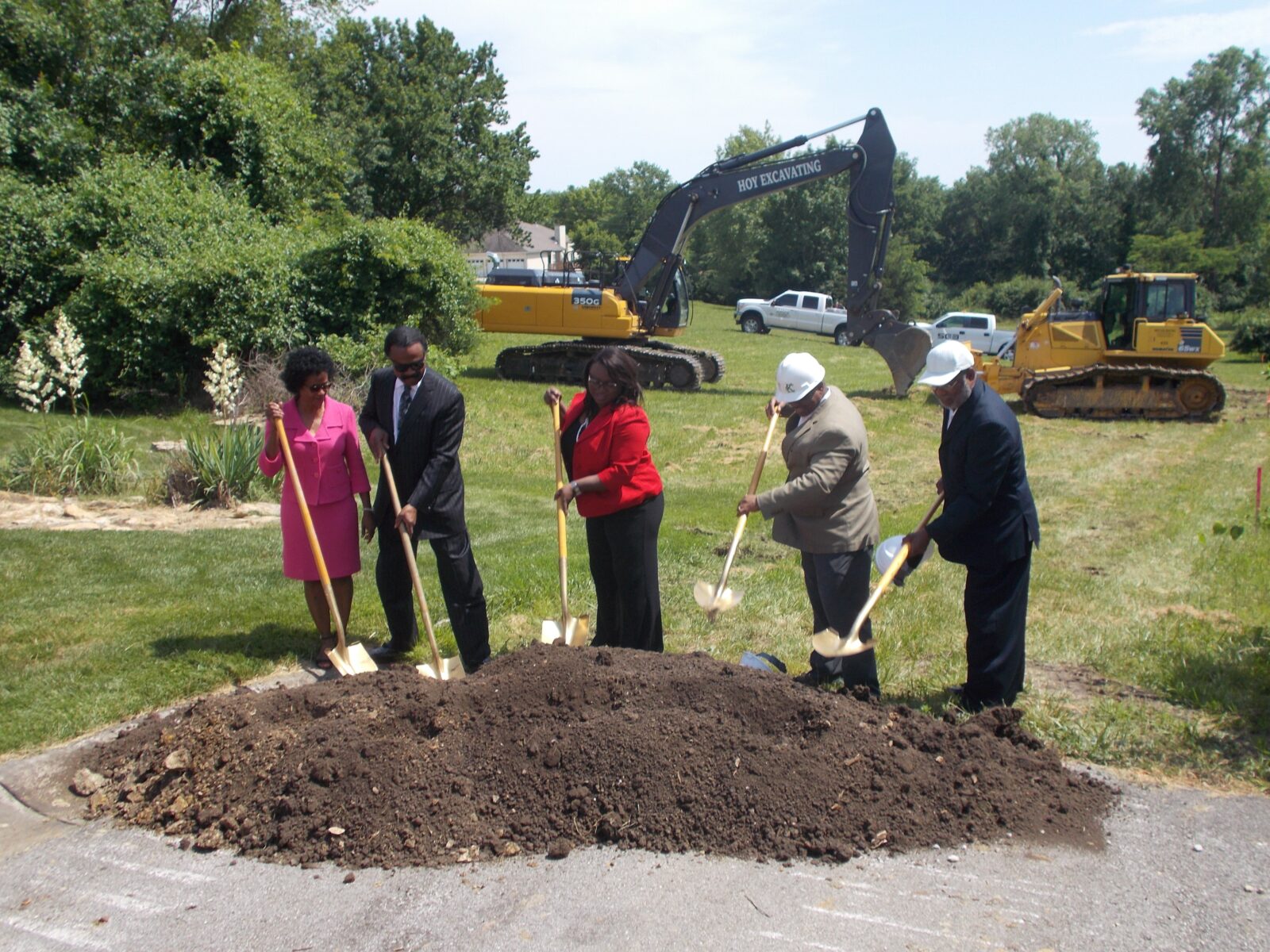 Five people symbolically breaking ground with shovels.