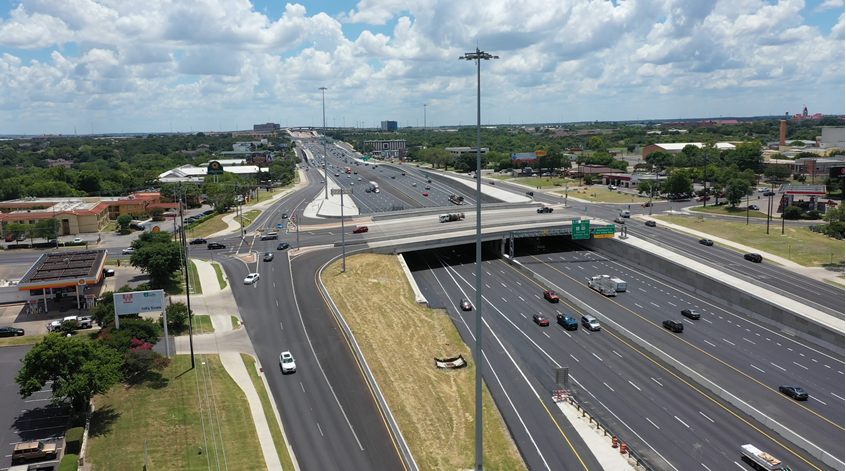 Image of the grade-separated intersection of a highway and a surface street, with high mast lighting poles visible.