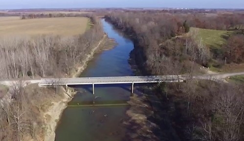 Image of a small river with a bridge over it.